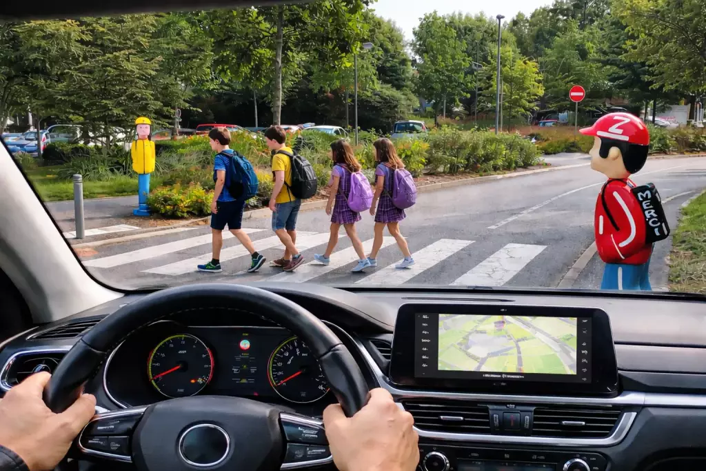 Vue conducteur : figurine SERAC bien visible avant un passage piéton près d'une école