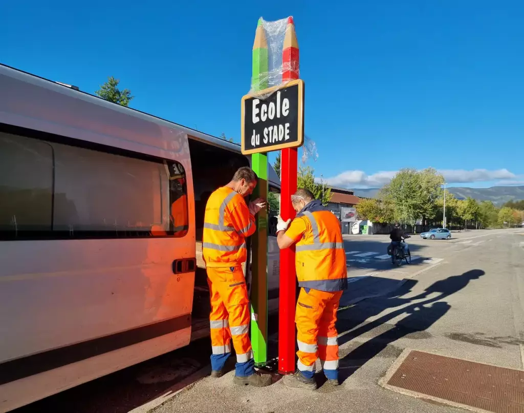Techniciens installant un totem « École » sans gros travaux de voirie