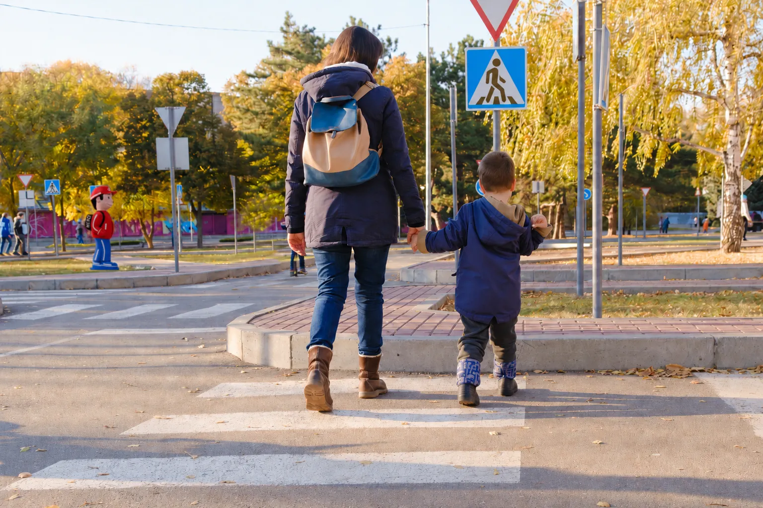 Parent et enfant traversant un passage piéton devant une école